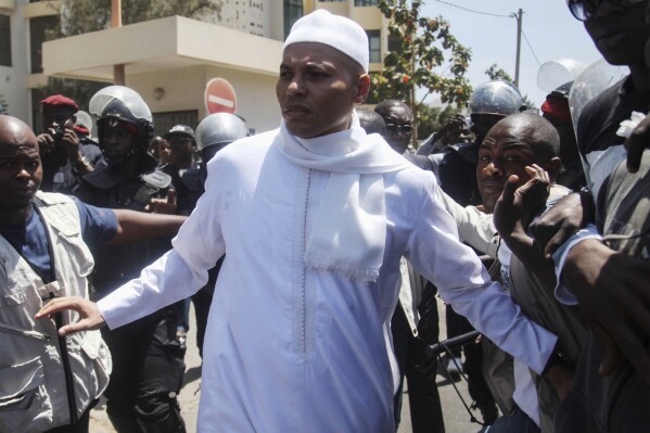 FILE - Karim Wade, centre, son of former Senegalese President Abdoulaye Wade, is surrounded by security as he leaves the office of the special prosecutor investigating him on charges of embezzled funds, in Dakar, Senegal, on March 15, 2013. Son of former Senegal president, Karim Wade, renounced his French nationality paving the way for him to run in next month’s elections. (AP Photo, File)