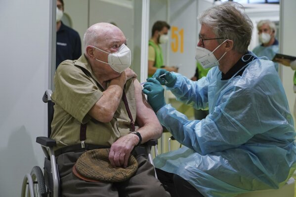 A doctor inoculates Herri Rehfeld, 92, against the new coronavirus with the Pfizer/BioNTech vaccine at the vaccination center at the Messe Berlin trade fair grounds on the center's opening day in Berlin, Germany, Monday, Jan. 18, 2021. The center is the third to open in Berlin. Three more are to open in coming weeks once shipments of the Pfizer/BioNTech and Moderna vaccines pick up pace. (Sean Gallup/Getty Images via AP, Pool)