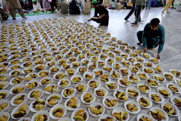 Volunteer arrange food plates to be distributed among people for breaking their fast during the Muslim's holy fasting month of Ramadan, in Lahore, Pakistan, Tuesday, March 12, 2024. (AP Photo/K.M. Chaudary)