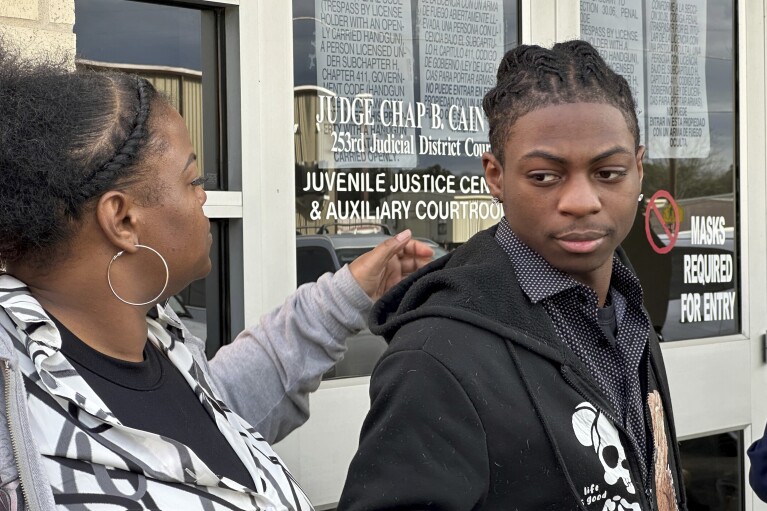 Daryl George, an 18-year-old high school student, and his mother, Daresha George, stand in court in Anawaque, Texas, Wednesday, Jan. 24, 2024. A judge on Wednesday ordered a trial next month to determine whether George can continue to be punished by his district for refusing to change his hairstyle, which he and his family say is protected by a new state law.  (AP Photo/Juan A. Lozano)