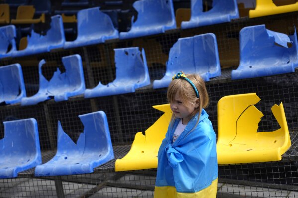 A young girls stands at an installation ahead of the Group E match between Romania and Ukraine at the Euro 2024 soccer tournament in Munich, Germany, Monday, June 17, 2024. A poignant installation has been unveiled ahead of Ukraine’s first match at the European Championship. A destroyed stand from Kharkiv’s Sonyachny stadium that was built for Euro 2012 has been displayed in a square in Munich ahead of the team’s opener against Romania. (AP Photo/Ariel Schalit)