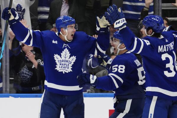 Toronto Maple Leafs' Justin Holl (3) celebrates his goal against the Ottawa Senators with tMichael Bunting and Auston Matthews during the third period of an NHL hockey game Saturday, Oct. 15, 2022, in Toronto. (Frank Gunn/The Canadian Press via AP)