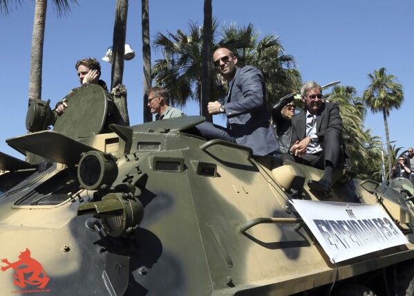 Dolph Lundgren, from second left, Jason Statham, and Harrison Ford ride atop an armored vehicle during a photo call for The Expendables 3 at the 67th international film festival, Cannes, southern France, Sunday, May 18, 2014. (Photo by Joel Ryan/Invision/AP, File)