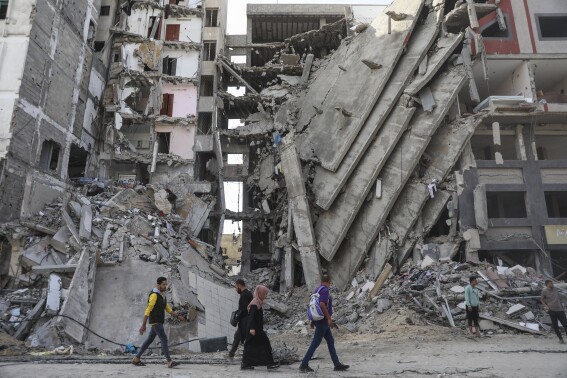 Palestinians walk through destruction in Gaza City on Friday, Nov. 24, 2023, as the temporary ceasefire between Israel and Hamas took effect. (AP Photo/Mohammed Hajjar)