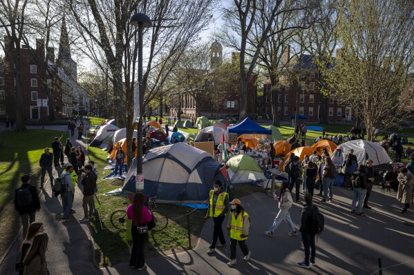 FILE - Students protesting against the war in Gaza, and passersby walking through Harvard Yard, are seen at an encampment at Harvard University in Cambridge, Mass., on April 25, 2024. Participants at the Harvard encampment protesting the war between Israel and Hamas announced they were voluntarily ending their occupation of Harvard Yard. The student protest group said in a statement that the encampment “outlasted its utility with respect to our demands,” and interim Harvard University President Alan Garber agreed to pursue a meeting between those involved in the protest and university officials. (AP Photo/Ben Curtis, File)