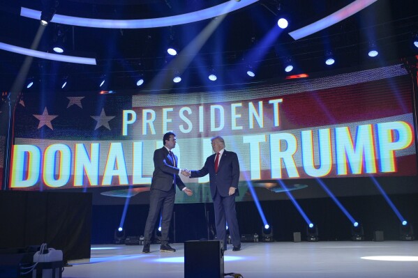 FILE - Former President Donald Trump, right, shakes hands with Turning Point CEO Charlie Kirk before speaking during the Turning Point USA Student Action Summit, July 23, 2022, in Tampa, Fla. The nonprofit rocketed to prominence by latching on to Trump’s 2016 campaign and has raised roughly a quarter-billion dollars since, much of it spent cultivating conservative influencers and hosting glitzy events. The organization also enriched Kirk and his allies, according to an Associated Press review of public records. (AP Photo/Phelan M. Ebenhack, File)