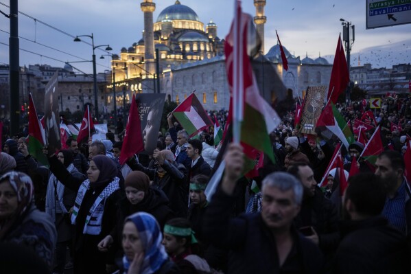 People demonstrate next to Yeni Cami (New Mosque) to show solidarity with Palestinians amid the ongoing war in Gaza, in Istanbul, Turkey, Monday, Jan. 1, 2024. Tens of thousands gathered in Istanbul to rally against the war in Israel on the first day of the new year. (AP Photo/Francisco Seco)