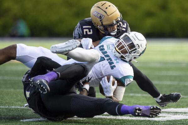 Coastal Carolina running back Braydon Bennett (1) gets tackled by James Madison linebacker Jailin Walker (25) and safety Josh Sarratt (12) during the second half of an NCAA college football game in Harrisonburg, Va., Saturday, Nov. 26, 2022. (Daniel Lin/Daily News-Record via AP)