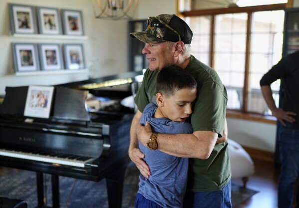Eleven-year-old adopted William Visser hugs his grandfather Kelly Monday, May 13, 2024, in Sterling, Colorado. (AP Photo/Jack Dempsey)