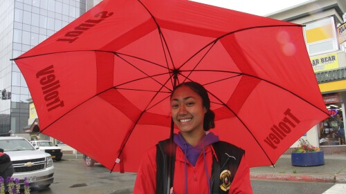 Naomi Rupena-Tuayo uses an umbrella to protect herself from intermittent rain as she stands outside all day for her job in the tourism industry, Thursday, June 29, 2023, in downtown Anchorage, Alaska.  A year after wildfires in Alaska burned enough land to cover the state of Connecticut, 2023 is on track for the slowest start to the wildfire season in three decades thanks to a cooler, wetter climate.  (AP Photo/Mark Thiessen)