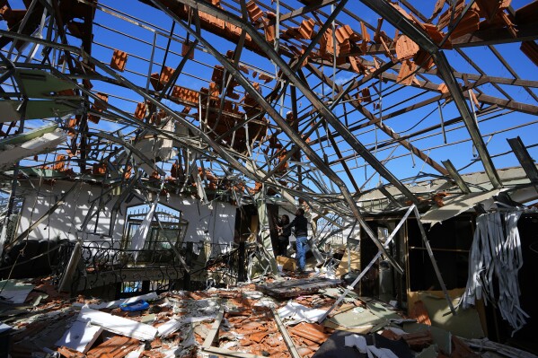 Workers inspect their office at a destroyed warehouse that was attacked on Monday by Israeli airstrikes, at an industrial district in the southern coastal town of Ghazieh, Lebanon, Tuesday, Feb. 20, 2024. Israeli warplanes carried out at least two strikes near the southern port city of Sidon in one of the largest attacks near a major city, wounding a dozen of people, Lebanese state media said. (AP Photo/Bilal Hussein)