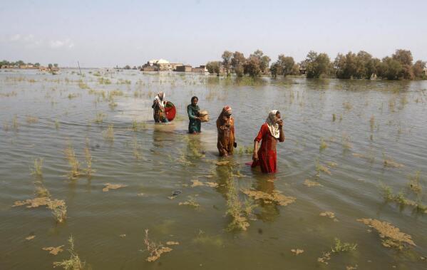 Pakistani women wade through floodwaters as they take refuge in Shikarpur district of Sindh Province, of Pakistan, Friday, Sep. 2, 2022. Pakistani health officials on Thursday reported an outbreak of waterborne diseases in areas hit by recent record-breaking flooding, as authorities stepped up efforts to ensure the provision of clean drinking water to hundreds of thousands of people who lost their homes in the disaster. (AP Photo/Fareed Khan)