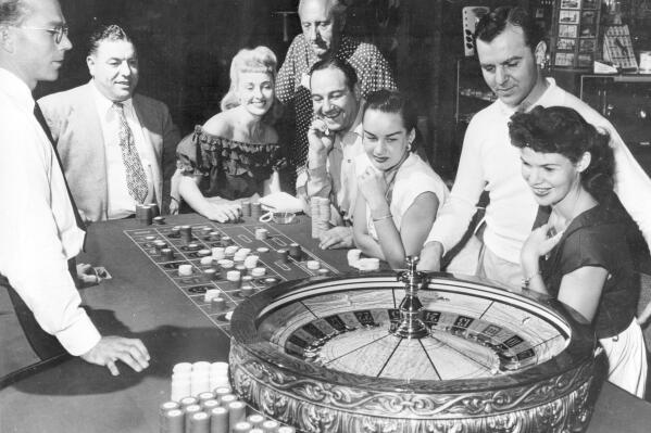 FILE - People are shown at one of the gaming tables at the Flamingo Casino in Las Vegas, Nev., on May 24, 1955. The Flamingo Las Vegas has begun celebrating its 75th birthday ahead of the Dec. 26, 1946, anniversary of Benjamin "Bugsy" Siegel and Meyer Lansky opening a 105-room property on what is now Las Vegas Boulevard. Downtown, the El Cortez Hotel & Casino has commemorated 80 years since opening in November 1941 with 59 rooms. (AP Photo/File)