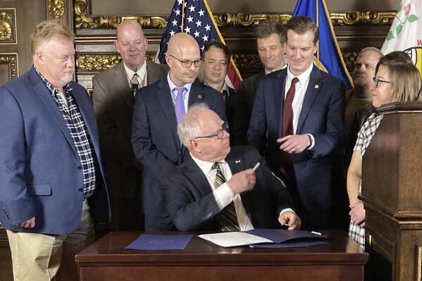 Democratic Minnesota Gov. Tim Walz hands one of the pens he used to sign a bill extending unemployment benefits for laid-off workers at Northshore Mining to state Sen. Grant Hauschild, D-Hermantown, during a ceremony at the State Capitol in St. Paul, Minn., on Wednesday, Jan. 25, 2023. It was the second bill that Walz has signed since the 2023 legislative session convened Jan. 3. (AP Photo/Steve Karnowski)