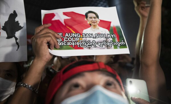 Myanmar nationals living in Thailand hold pictures of Myanmar leader Aung San Suu Kyi and display mobile phones with flash lights, during a protest in front of the Myanmar Embassy in Bangkok, Thailand, Thursday, Feb. 4, 2021. The military announced Monday that it will take power for one year, accusing Suu Kyi's government of not investigating allegations of voter fraud in recent elections. Suu Kyi's party swept that vote and the military-backed party did poorly. The state Election Commission has refuted the allegations. (AP Photo/Sakchai Lalit)