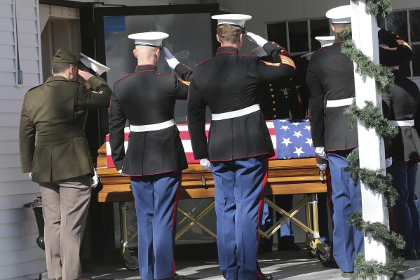 Marines salute the body of the late Marine Capt. Jack Casey, who died in a helicopter crash with four other Marines, at the Wiggin-Purdy-McCooey-Dion Funeral Home in Dover, N.H., on Tuesday, Feb. 20, 2024. Casey was one of the five Marines killed when their helicopter went down in the mountains outside San Diego during a storm. (Deb Cram/Foster's Daily Democrat via AP)