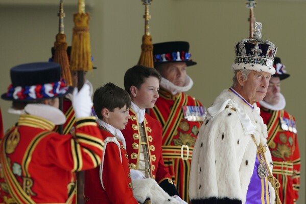 FILE - Britain's King Charles III, right, arrives to receive a royal salute from members of the military in the gardens of Buckingham Palace, following his coronation, in London, Saturday May 6, 2023. A year after the death of Queen Elizabeth II triggered questions about the future of the British monarchy, King Charles III’s reign has been marked more by continuity than transformation, by changes in style rather than substance. (Peter Byrne/Pool Photo via AP, File)