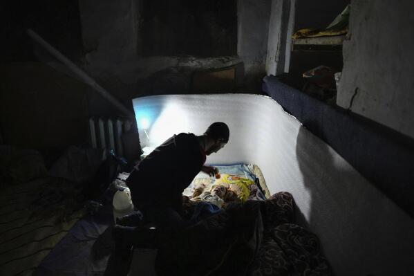 A man plays with a baby in a bomb shelter in Mariupol, Ukraine, Sunday, March 6, 2022. (AP Photo/Evgeniy Maloletka)