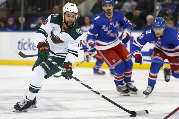 Minnesota Wild's Jordan Greenway (18) skates up ice with the puck while being trailed by New York Rangers' Chris Kreider (20) and Alexis Lafreniere (13) during the second period of an NHL hockey game Friday, Jan. 28, 2022, in New York. (AP Photo/John Munson)