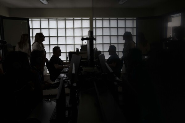 Head of Anti Mafia force (DIA), Carla Durante, left, is silhouetted has she talks with her team in the wire-tape room of the DIA headquarters in Lecce, Italy, Tuesday, May 21, 2024. (ĢӰԺ Photo/Alessandra Tarantino)