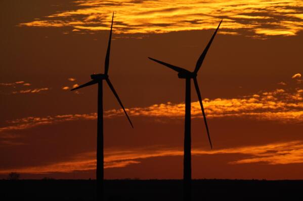 FILE - Wind turbines are silhouetted against the sky at sunset Dec. 17, 2021, near Ellsworth, Kan. The 300-foot-tall turbines are among the 134 units comprising the Post Rock Wind Farm. The Republican chairman of the Kansas Senate Utilities Committee is pushing several measures that green energy officials say would make it harder to put up new wind turbines or solar farms in the state, though he argues that he's protecting landowners. (AP Photo/Charlie Riedel, File)
