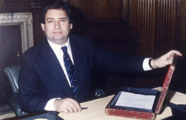 FILE - Preparing his budget, Britain's Chancellor of the Exchequer, Nigel Lawson, with his famous battered red Budget Box, in his office at the Treasury, London, March 10, 1987. Lawson, the tax-cutting UK Treasury chief under the late Margaret Thatcher and a lion of Conservative politics in the late 20th century has died. He was 91. (AP Photo/Gerald Penny, File)
