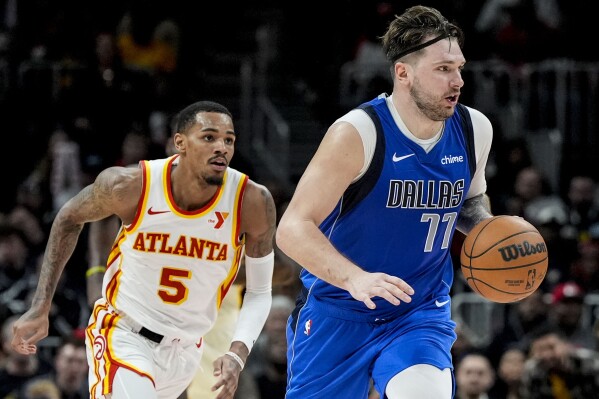 Dallas Mavericks guard Luka Doncic (77) moves against Atlanta Hawks guard Dejounte Murray (5) during the second half of an NBA basketball game, Friday, Jan. 26, 2024, in Atlanta. (AP Photo/Mike Stewart)