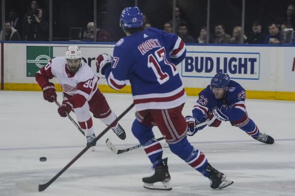 Detroit Red Wings center Joe Veleno (90) goes after loose puck against New York Rangers center Kevin Rooney (17) and New York Rangers defenseman Adam Fox (23) during second period of NHL hockey game, Saturday April 16, 2022, in New York. (AP Photo/Bebeto Matthews)