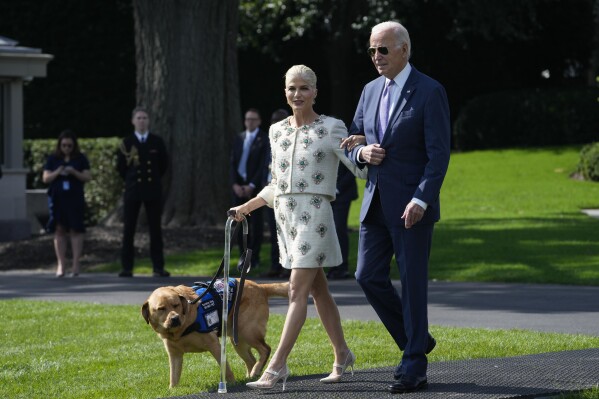President Joe Biden walks with actress Selma Blair and Blair's service dog Scout as they arrive for an event to celebrate the Americans with Disabilities Act on the South Lawn of the White House, Monday, Oct. 2, 2023, in Washington. (AP Photo/Susan Walsh)