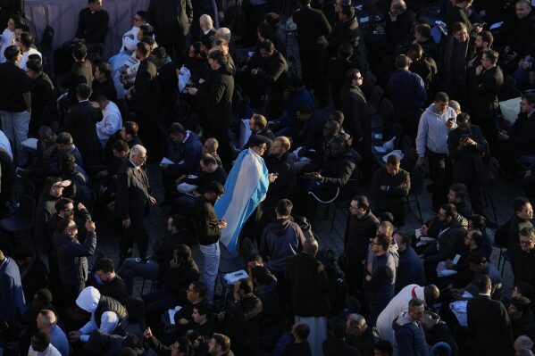 A faithful wearing a flag from Argentina arrives for the funeral of Pope Francis in St. Peter's Square at the Vatican, Saturday, April 26, 2025. (AP Photo/Gregorio Borgia)