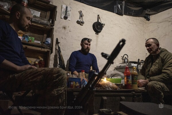 In this photo provided by Ukraine's 33rd Mechanised Brigade press service, servicemen prepare a festive dinner on Christmas Eve in a shelter on the frontline in the Dnipropetrovsk region, Ukraine, Tuesday, Dec. 24, 2024. (Volodymyr Petrov/Ukraine's 33rd Mechanised Brigade via AP)