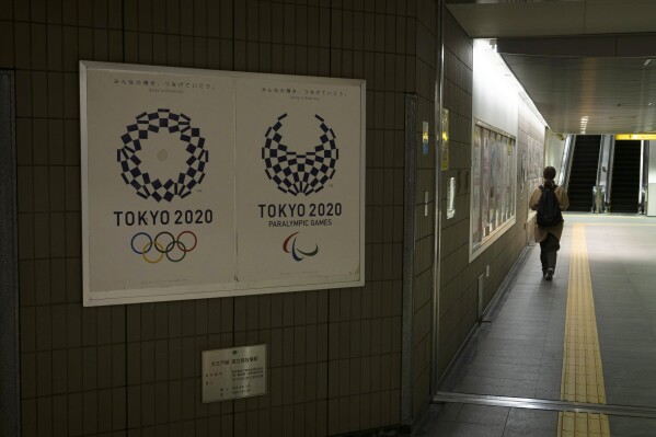 FILE - A commuter leaves a train station adorned with posters promoting the Tokyo 2020 Olympics in Tokyo, on March 23, 2020. An executive at Japanese publishing house Kadokawa was found guilty Tuesday, Oct. 10, 2023 of bribing a former Tokyo Olympics organizing committee member. (AP Photo/Jae C. Hong, File)