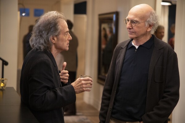 This image released by HBO shows Richard Lewis, left, with Larry David in a scene from Season 10 of "Curb Your Enthusiasm." Lewis, an acclaimed comedian known for exploring his neuroses in frantic, stream-of-consciousness diatribes while dressed in all-black, leading to his nickname “The Prince of Pain,” has died. He was 76. He died at his home in Los Angeles on Tuesday night after suffering a heart attack, according to his publicist Jeff Abraham. (John P. Johnson/HBO via AP)