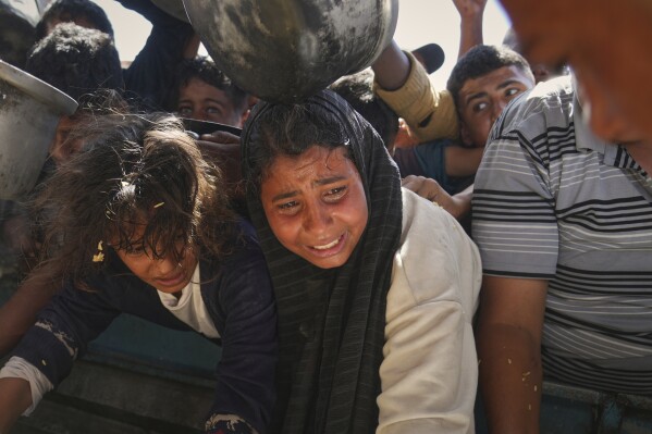 Palestinians struggle to obtain donated food at a community kitchen in Khan Younis, in the southern Gaza Strip, Friday, May 9, 2025. (AP Photo/Abdel Kareem Hana)