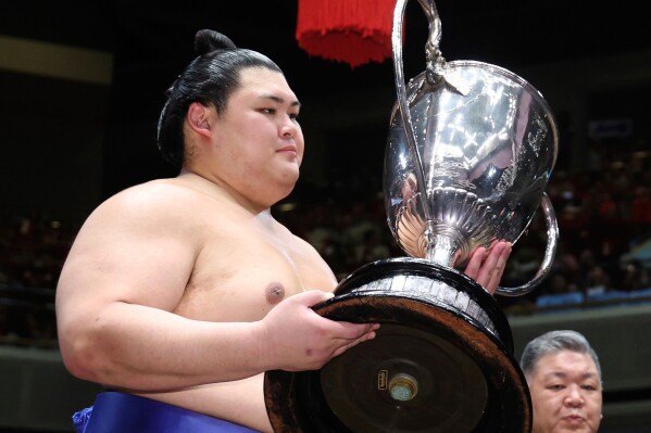 Onosato receives the trophy after winning in a sumo wrestling tournament at Ryogoku Kokugikan arena in Tokyo, Sunday, May 25, 2025. (Kyodo News via AP)