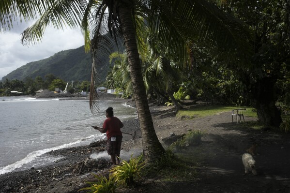 A man burns fallen leaves on a beach in Te Aupoo, Tahiti, French Polynesia, Friday, Jan. 13, 2024. (AP Photo/Daniel Cole)