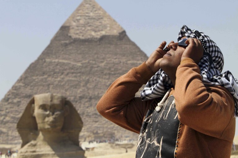 FILE - An man uses special glasses to view a partial solar eclipse as people gather near the Sphinx at the Giza Pyramids on the outskirts of Cairo, Egypt, Friday, March 20, 2015. The partial eclipse was visible across Europe and parts of Asia and Africa, while sky-gazers in the Arctic were treated to a perfect view of a total solar eclipse as the moon completely blocked out the sun in a clear sky. (AP Photo/Khaled Kamel, File)