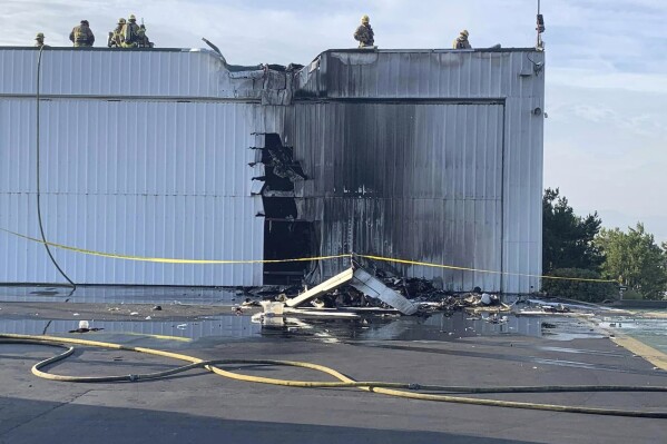 This photo provided by the San Bernardino County Fire Department shows fire department personnel responding to a small plane that crashed into a hanger at Cable Airport in Upland, Calif., Sunday, July 30, 2023. (San Bernardino County Fire Department via AP)
