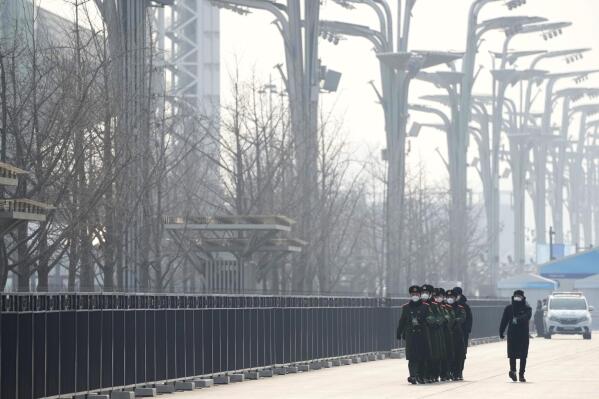 FILE - Chinese paramilitary police walk in formation on the Olympic Green near the edge of the closed-loop area at the 2022 Winter Olympics in Beijing, Jan. 30, 2022. (AP Photo/Mark Schiefelbein, File)