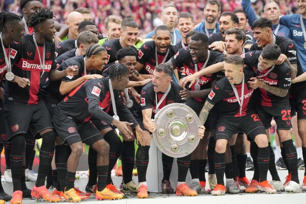 Leverkusen's Granit Xhaka, centre, celebrates with the trophy as his team won the German Bundesliga soccer match between Bayer Leverkusen and FC Augsburg at the BayArena in Leverkusen, Germany, Saturday, May 18, 2024. Bayer Leverkusen have won the Bundesliga title for the first time. It is the first team in Bundesliga history, that won the championship unbeaten for the whole season. (AP Photo/Martin Meissner)