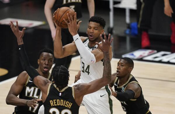 Milwaukee Bucks' Giannis Antetokounmpo (34) passes the ball as Atlanta Hawks' Cam Reddish (22) defends during the first half of Game 4 of the NBA basketball Eastern Conference finals Tuesday, June 29, 2021, in Atlanta. (AP Photo/Brynn Anderson)