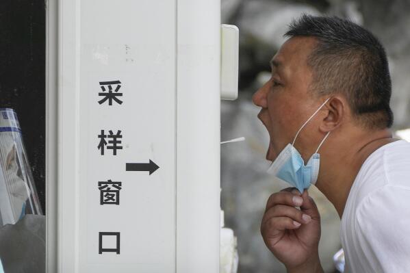 A man gets a throat swab at a testing site as people are required for a negative COVID test in the last 72 hours before entering some buildings and using public transportation in Beijing, Tuesday, July 19, 2022. Authorities in southern China apologized for breaking into the homes of people quarantined for being suspected of contracting COVID-19 in the latest example of heavy-handed measures that have sparked a rare public backlash. (AP Photo/Andy Wong)