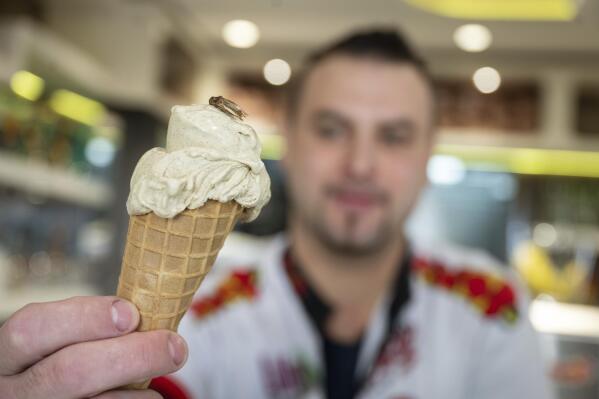 Thomas Micolino, owner of Eiscafe Rino, holds an ice cream cone in Rottenburg am Neckar, Germany, Wednesday, March 1, 2023. A German ice cream parlor is selling a new kind of special treat: insect flavor with dried brown crickets as topping. (Marijan Murat/dpa via AP)