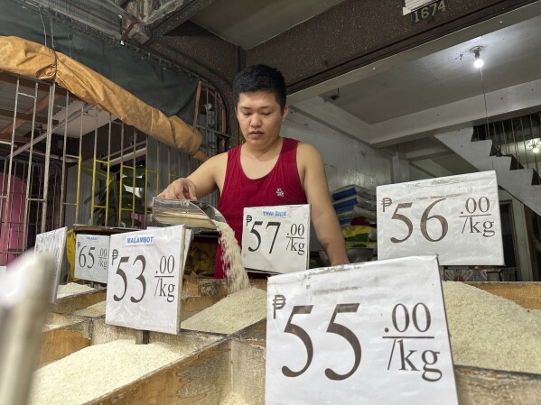 Ronnel Gardon tends rice supplies at a shop in Manila on Thursday, Sept. 21, 2023. Food stores in Manila are losing money, with prices increasing rapidly since Sept. 1 and customers who used to snap up supplies in bulk buying smaller quantities. (AP Photo/Joeal Calupitan)