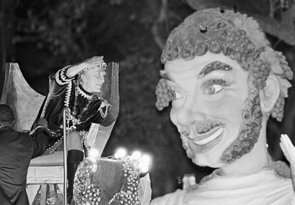 Bacchus the XVII, also known as Kirk Douglas, tosses doubloons from a carnival float on Mar. 4, 1984 in New Orleans. The popular Bacchus parade was one of several Sunday. The celebrations end with Rex and other Mardi Gras extravaganzas on Tuesday. (AP Photo/Bill Haber, file)