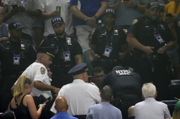 New York Police surround one of the protesters who disrupted play between Coco Gauff, of the United States, and Karolina Muchova, of the Czech Republic, during the women's singles semifinals of the U.S. Open tennis championships, Thursday, Sept. 7, 2023, in New York. (AP Photo/Charles Krupa)