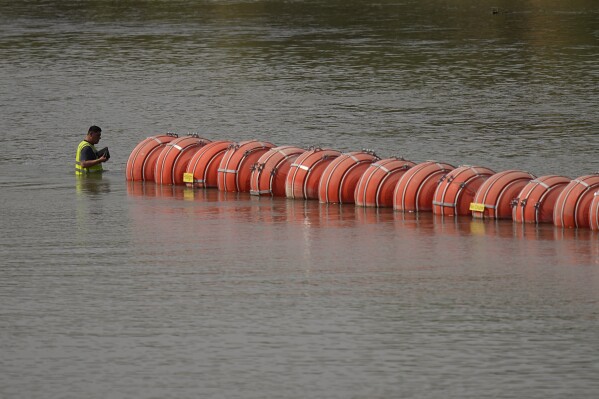 A worker inspects buoys being used as a barrier along the Rio Grande, Monday, Aug. 21, 2023, in Eagle Pass, Texas. (AP Photo/Eric Gay)