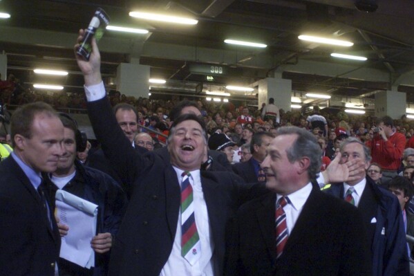 FILE - Former Wales players Barry John, center, and Gareth Edwards, right, attend the opening ceremony of the 1999 Rugby World Cup in Cardiff, Jan. 10, 1999. Welsh rugby great Barry John has died at the age of 79. He played 25 games for Wales and inspired the British and Irish Lions’ famous series victory over New Zealand in 1971 before retiring at the age of 27. John’s family announced his death Sunday Feb. 4, 2024. in a statement released to British media, saying he died peacefully in the hospital. (David Jones/PA via AP, File)