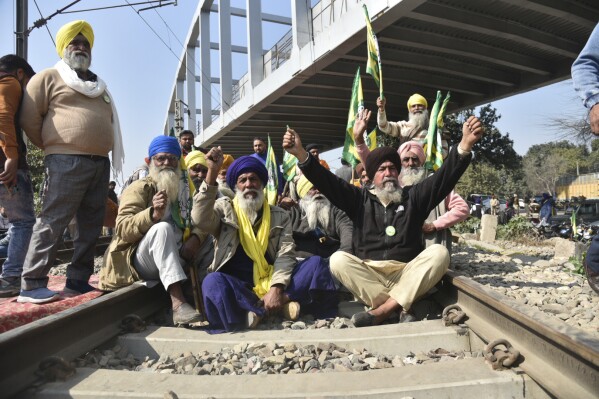 Protesting Indian farmers shout slogans sitting on train tracks as they demand guaranteed prices for their produce at Vallah village, outskirts of Amritsar, Punjab, India, Thursday, Feb.15, 2024. The farmers are also pressing the government to follow through on its promise to double their income, waive their loans and withdraw legal cases brought against them during earlier 2021 protests, when they camped on the capital’s outskirts to demonstrate against controversial agriculture laws. (AP Photo/Prabhjot Gill)