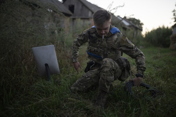 A Ukrainian serviceman nicknamed Bakeneko sets up satellite communications before a drone attack in the outskirts of Kremmina, Ukraine, Sunday, Aug. 20, 2023. (AP Photo/Bram Janssen)